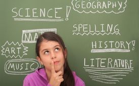 girl in front of chalkboard with class names written on it